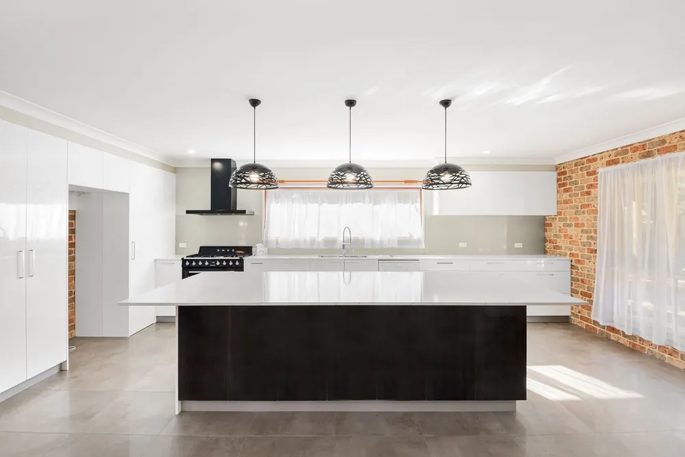 Bright modern kitchen with three black pendant lights over an island bench